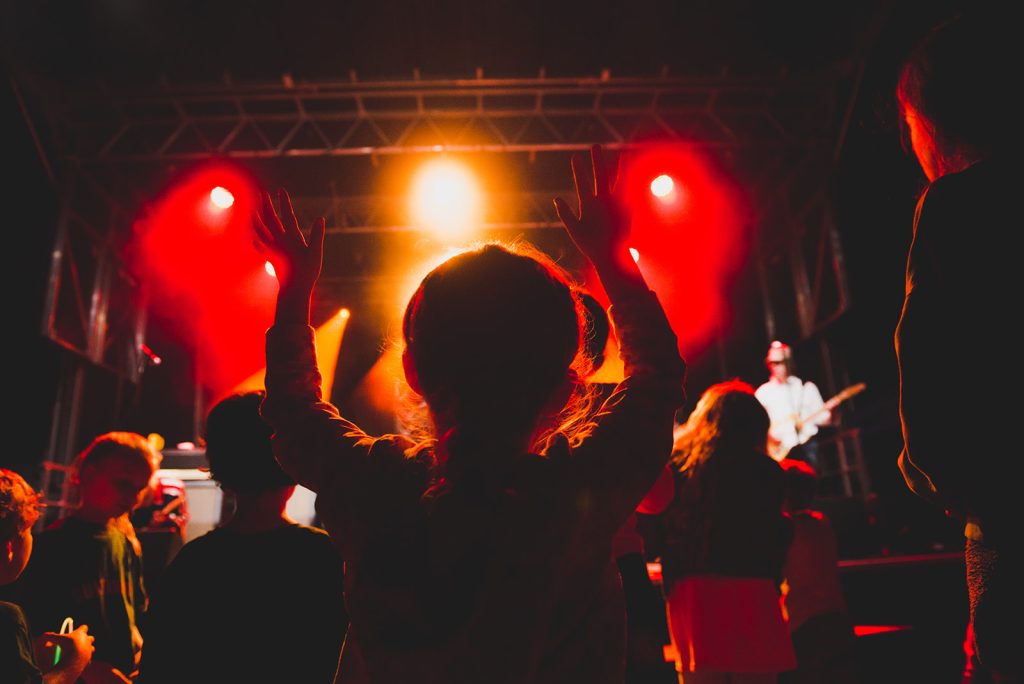 Kid wathing the stage under red lights in the evening