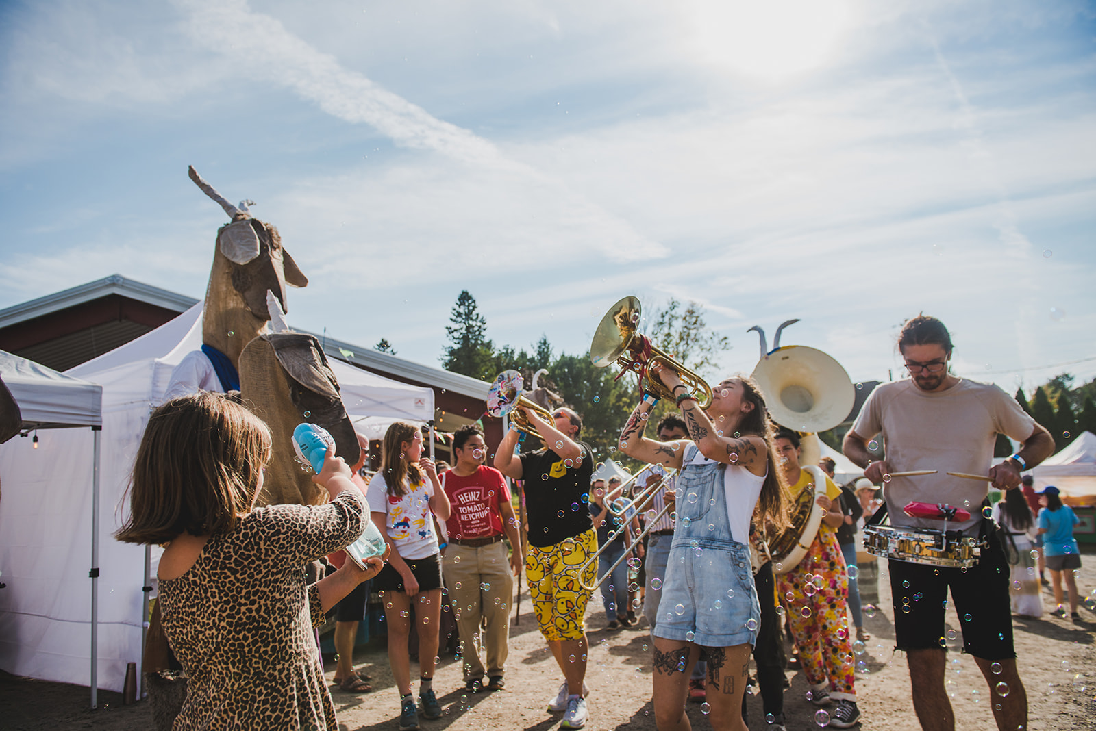 Brass band parading in a festival environment with partially cloudy blue sky in the background