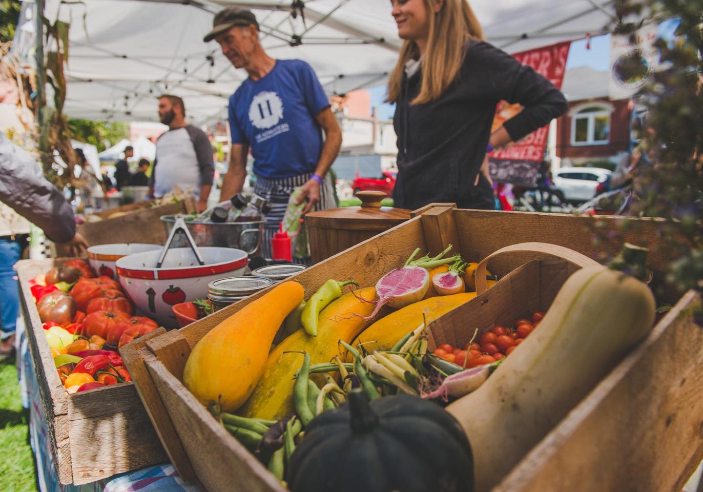 Tony From Headwaters Farm speaks with an attendee at their vendor booth, filled with fresh produce